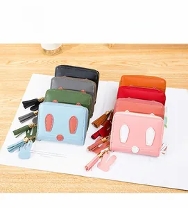 Detailed view of colorful rabbit zipper wallets with tassels on a wooden surface