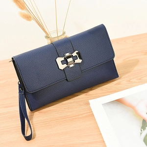 Navy blue lychee texture crossbody bag with silver bow clasp on light wooden surface