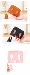 Close-up of rabbit zipper wallets in orange black and pink with tassels and ear charms