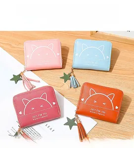 Detail of colorful mini zip wallets with cute cat prints and tassel charms on wood background