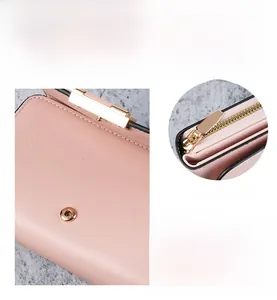 Detail of light pink women's wallet showing golden snap button and smooth zipper system