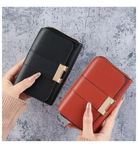Detail of short leather wallets with gold buckles and zipper in black and red colors