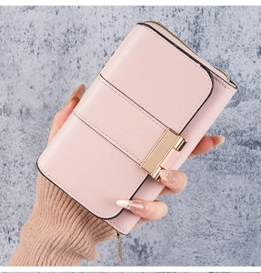 Close-up of pink leather long wallet with gold buckle and smooth texture held by hand