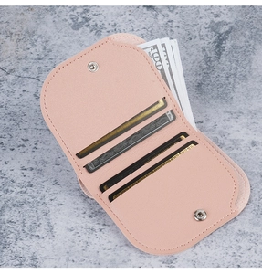 Dettaglio portafoglio sottile rosa con tre slot per carte e chiusura a scatto