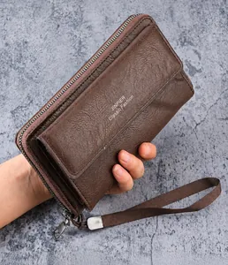 Macro shot of brown leather clutch bag with litchi grain texture and wrist strap
