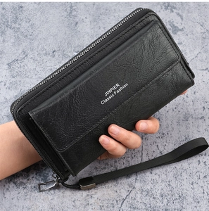 Detail of black textured leather clutch bag with wrist strap and zippered compartment
