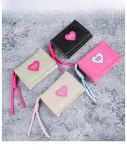 Flat lay of colorful heart embroidered leather mini wallets with braided wrist straps