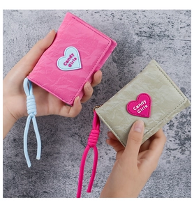 Close-up of minimalist folded wallets with heart patches and woven cotton lanyards
