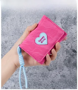 Close-up of pink trifold wallet with heart patch and blue woven lanyard details
