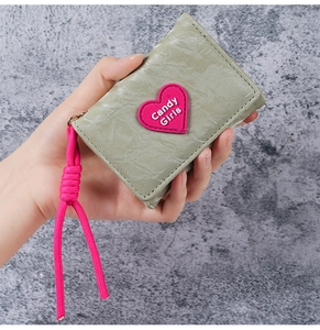 Detail of grey-green heart wallet featuring Candy Girls patch and pink woven strap