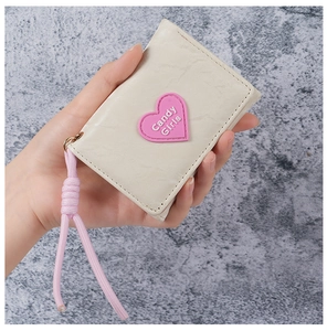 Close-up of beige quilted wallet with pink heart patch and matching wrist strap