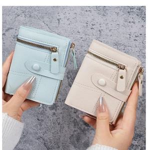 Close-up of minimalist short PU leather wallets in light blue and beige with zipper detail