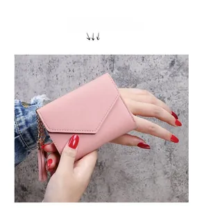 Dettaglio di un portafoglio in pelle rosa chiaro con nappa tenuto in mano
