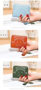 Detailed close-up of cute cat print wallets in blue, orange, and green with tassel charms