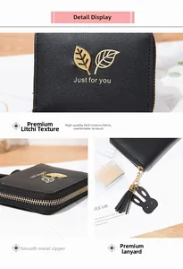 Detail showing litchi grain texture, golden leaf hardware and cute rabbit charm on black wallet