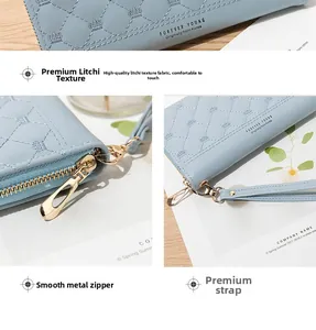 Detail of light blue long wallet showing crown embroidery, diamond quilting, and metal zipper