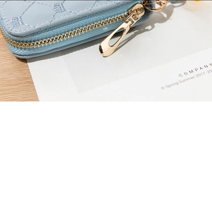 Close-up of light blue quilted purse featuring crown embroidery and gold teardrop zipper