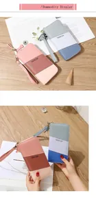 Detailed view of color-block long wallet with decorative tassel and bow wristlet strap