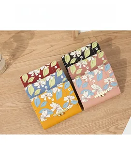 Flat lay of mini floral PU leather wallets in various colors on a wooden surface