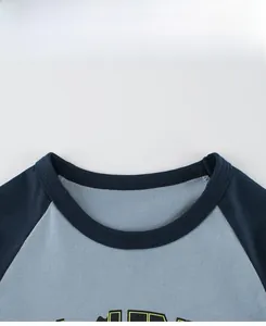 Detail of round raglan neckline on a light blue knit t-shirt with navy contrast trim