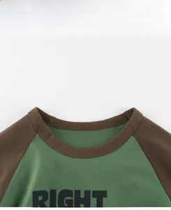 Detail of kids cotton T-shirt featuring green body, brown raglan sleeves and monster print