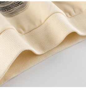 Detail view of beige sweatshirt featuring ribbed hem and stylish circular graphic print