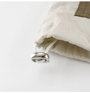 Macro detail of elastic drawstring with silver metal stopper on a woven nylon jacket