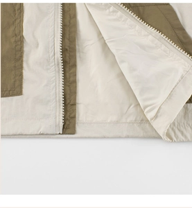 Detail view of woven jacket showing color-blocking design and white plastic steel zipper