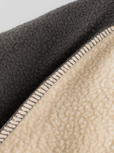 Close-up of grey fleece and creamy sherpa fleece fabric with detailed stitching