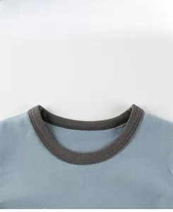 Detail view of cotton tee with contrast crew neck ribbing and text print on light blue fabric