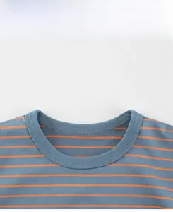 Détail du col rond rayé avec coutures sur tissu bleu-gris et rayures oranges