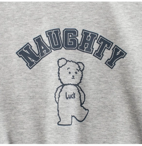 Macro detail of kids grey fleece sweatshirt featuring blue NAUGHTY text and bear print