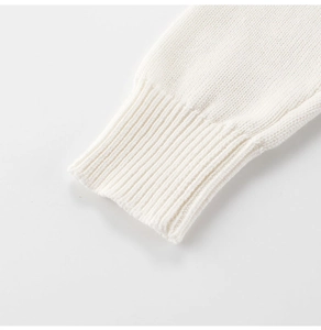 Detail of ribbed cuff on white knitted sweater showing premium soft cotton texture