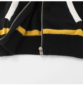 Detail of black and yellow striped knit sweater featuring a silver metal zipper and ribbed hem