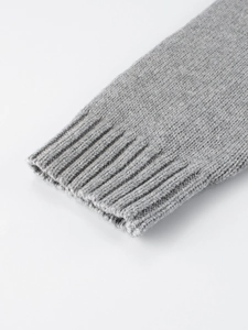 Close-up of grey knitted toddler sweater showing ribbed cuffs and soft wool texture