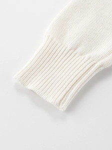 Close-up of white knit sweater showing high-quality ribbed cuffs and premium fabric texture