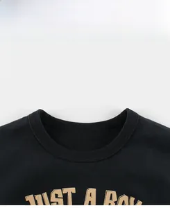 Detail of ribbed crew neck and 'JUST A BOY' letter print on boys' black cotton T-shirt