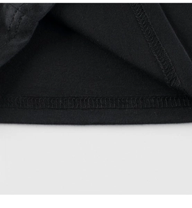 Close-up of neatly stitched hem and cotton fabric texture on a boys' dinosaur tee