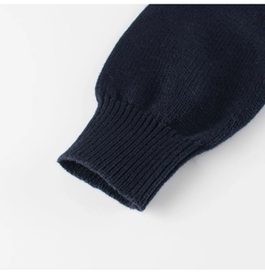 Dettaglio dei polsini a coste blu scuro di un cardigan in maglia di alta qualità