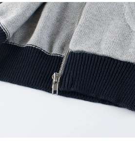 Dettaglio del tessuto a maglia grigio con bordo a costine blu e cerniera in metallo argento