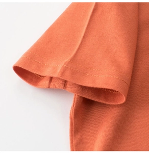 Detailed close-up showing the double-needle stitching on the orange cotton T-shirt sleeve