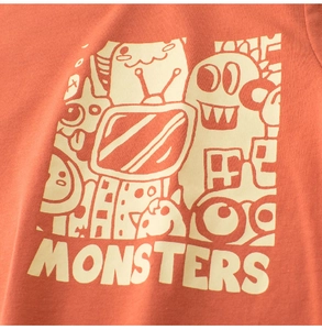 Close-up of monster doodle print on orange cotton kids' T-shirt with knit texture