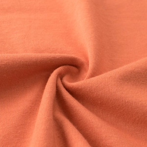 Detailed close-up of soft coral orange knitted cotton fabric texture and weave