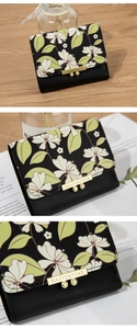 Detailed view of black floral wallet with white blossoms and golden metallic clasp