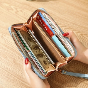 Long light blue zip wallet with wrist strap and phone compartment on wooden desk