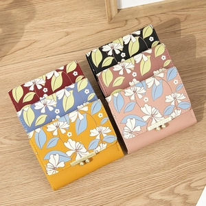 Set of 6 mini PU leather wallets with floral print and gold metal trim on wood background