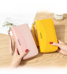 Dettaglio portafogli in pelle PU intrecciata rosa e gialla con cinturini su tavolo