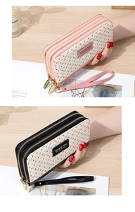 Close-up of triple zipper long wallet with logo pattern and detachable wrist strap