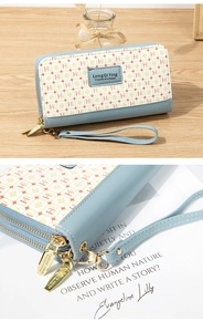 Detail of light blue faux leather long wallet with dual zippers and floral letter pattern