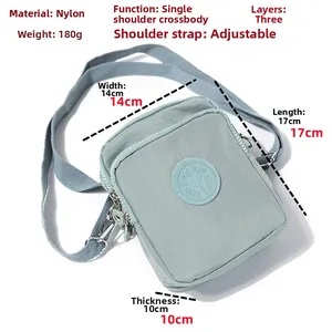 Detail view of pale green nylon crossbody bag with three zipper layers and adjustable strap